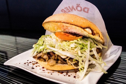 Kebap Sandwich von Pizza Engersdorf mit Fleisch, Salat und Sauce im Fladenbrot auf einem Teller