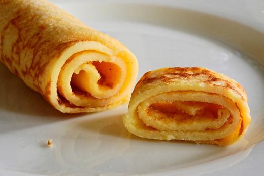 Gerollte Palatschinken mit süßer Füllung auf einem Teller von Pizza Engersdorf